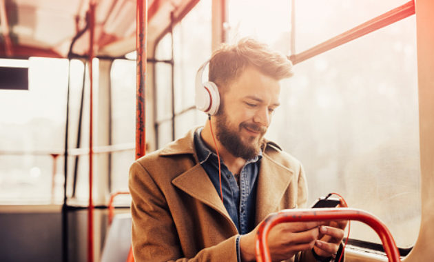 Charming man listening to music with headphones on a public bus
